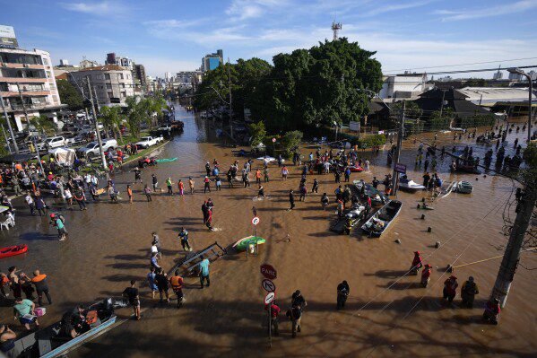Voluntarios se reúnen para ayudar a los residentes a evacuar un área inundada por lluvias torrenciales, en Porto Alegre, Brasil, el martes 7 de mayo de 2024. (Foto AP/Andre Penner)