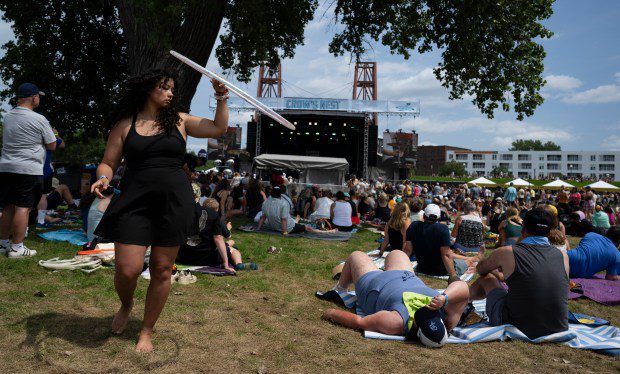 Una mujer sostiene un hula-hoop y baila detrás de una gran multitud de participantes del festival.