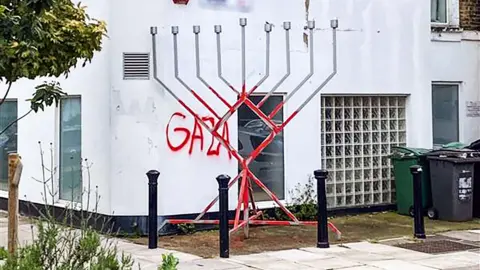 Candelabro CST con pintura roja y palabra. "Gaza" Escrito en la pared detrás