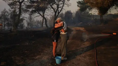 Reuters Marina Kalogerakou, de 24 años, abraza a su tía Eleonora Zoakou, de 48 años, durante un incendio forestal en Bentli, Grecia, el 12 de agosto de 2024