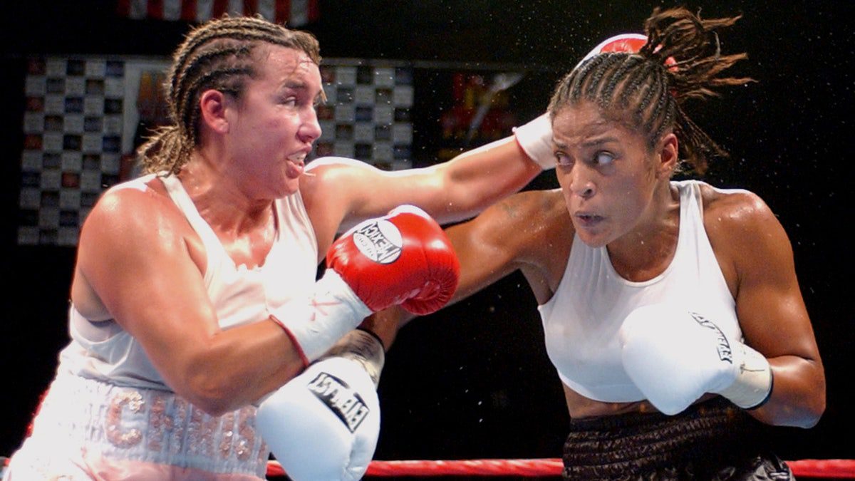 Christy Martin con trenzas en el cabello pelea con Laila Ali, ambas vestidas de blanco