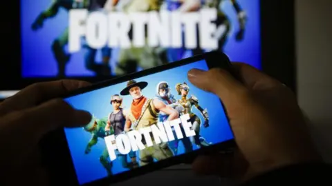 Getty Images Dos manos sosteniendo un teléfono móvil con el logo de Fortnite